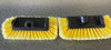 Two car wash brushes with yellow bristles and black holders on a gray surface.
